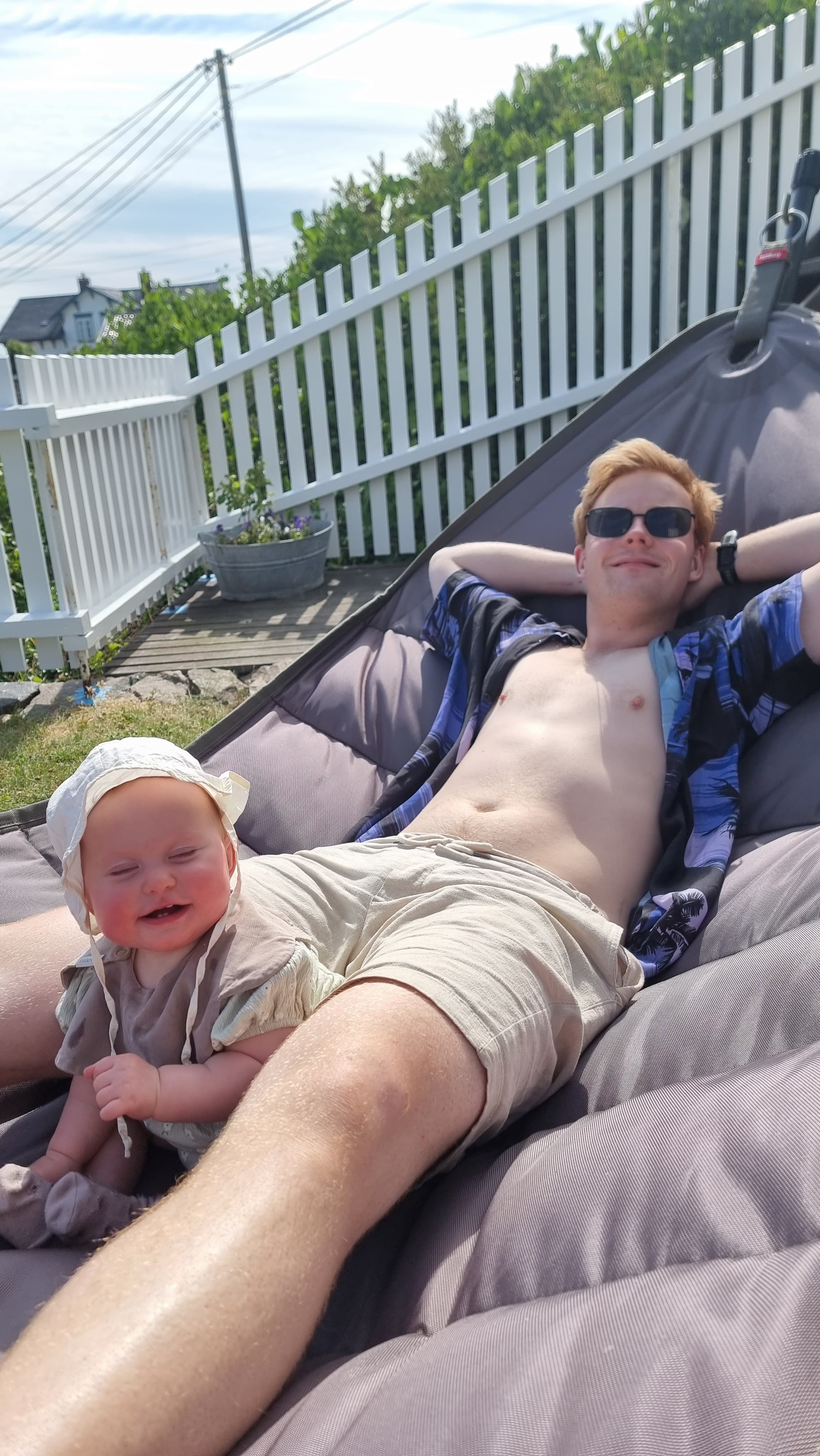 Ola og Olivia slapper av sammen i solen på en stor pute utendørs