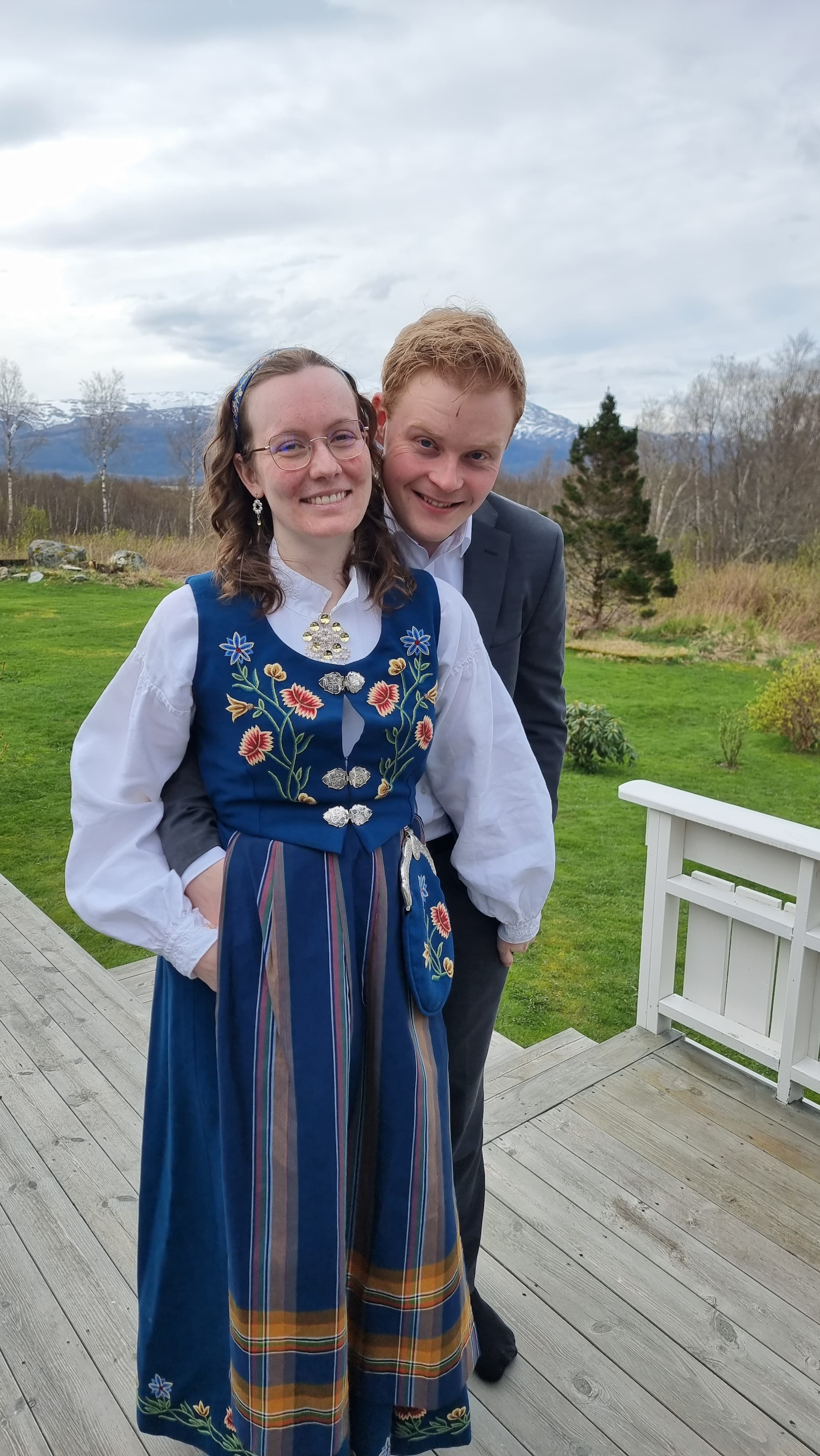 Ola og Kristine i dress og bunad sammen på en terrasse
