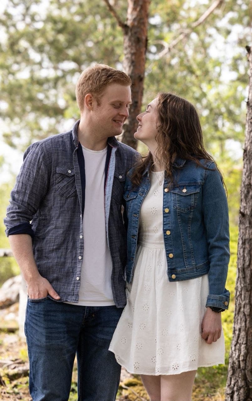 Ola og Kristine ser smilende på hverandre i en solfylt skog
